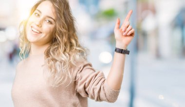 Sweatershirt izole arka plan dans mutlu ve neşeli, hareketli rahat ve kendinden emin müzik gülümseyen üzerinde giyen genç güzel sarışın kadın