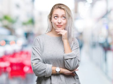 Genç Sarışın kadın elle çene düşünme hakkında soru, dalgın ifade izole arka plan yüzünden. Düşünceli yüzüyle gülümsüyor. Şüphe kavramı.