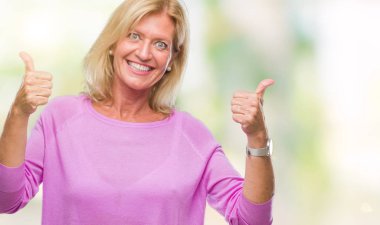 Orta yaş sarışın kadın el ile pozitif jest yapıyor izole arka plan başarı işareti yüzünden başparmak gülümseyen ve mutlu. Neşeli bir ifadeyle, kazanan jest kameraya bakıyor.