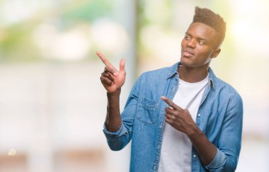 Gülümseyen ve iki elleri ve parmakları ile tarafına işaret kamera bakarak izole arka plan üzerinde genç Afro-Amerikan adam.