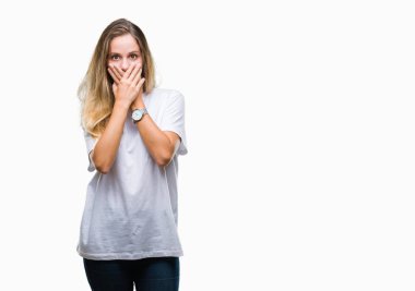 Genç güzel sarışın kadın üzerinde rahat beyaz t-shirt giyen arka plan ağız hata için elleriyle kapsayan şok izole. Gizli kavramı.