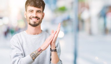 Genç yakışıklı adam giyen kazak izole üzerinde arka plan Clapping ve mutlu ve neşeli, gururlu gülümseyen birlikte eller alkış