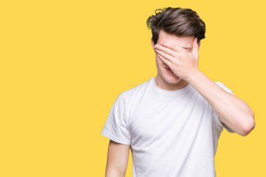 Gülümsüyor ve gözleri için sürpriz kapsayan yüz el ile gülüyor izole arka plan üzerinde rahat beyaz t-shirt giyen genç yakışıklı adam. Kör kavramı.