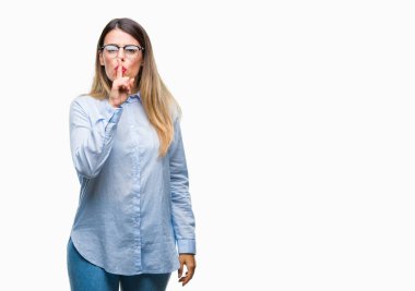 Dudaklarında parmak ile sessiz olmanı izole arka plan üzerinde gözlük takan genç güzel iş kadını. Sessizlik ve gizli kavramı.