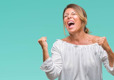 Gülümseyen ve başarı için çığlık orta yaş üst düzey İspanyol kadın izole arka plan çok mutlu ve heyecanlı kaldırdı, silah ile kazanan jest yapıyor. Kutlama kavramı.