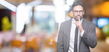 Genç yakışıklı iş adamı dudaklarında parmak ile sessiz olmanı izole arka plan üzerinde. Sessizlik ve gizli kavramı.