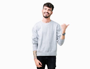 Seyir ve başparmak yanında yukarıyı mutlu yüz ile gülümseyen izole arka plan üzerinde sweatshirt giyen genç yakışıklı adam.