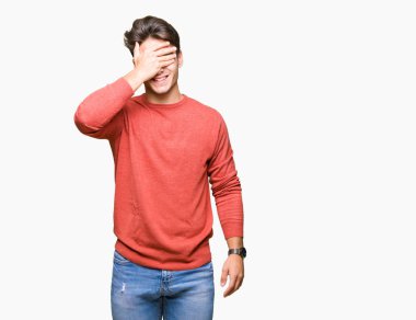 Yakışıklı genç gülümseyen ve gözler için sürpriz kapsayan yüz el ile gülüyor izole arka plan üzerinde. Kör kavramı.