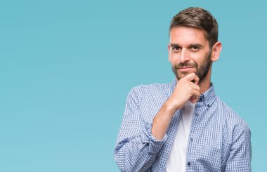 Emin çapraz kollar ve çeneme kaldırdı el ile gülümseme ile kameraya bakarak izole arka plan üzerinde beyaz t-shirt giyen genç yakışıklı adam. Pozitif düşünce.