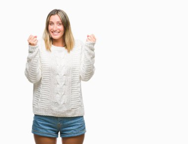 İzole arka plan üzerinde kutluyor kış kazak giyen genç güzel kadın şaşırttı ve başarı için kaldırdı kollarını açarak hayret ve gözleri açık. Kazanan kavramı.