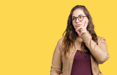 Artı boyutu genç kadın güzel üzerinde bir elbise ve deri ceket giyiyor arka plan çene düşünme hakkında soru, dalgın ifade üzerine el ile izole. Düşünceli yüzüyle gülümsüyor. Şüphe kavramı.