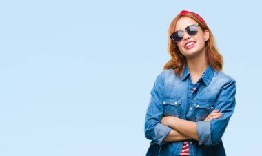 İzole arka çapraz silah kameraya bakarak ile gülümseyen güneş gözlüğü mutlu yüz giyen genç güzel kadın. Olumlu bir kişi.