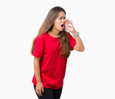 Bağırarak ve ağzı üzerinde el ile yan için çığlık izole arka plan üzerinde kırmızı t-shirt giyen genç güzel esmer kadın. İletişim kavramı.