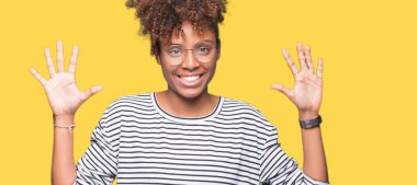 Güzel genç Afro-Amerikan kadın gözlük gösterilen ve parmakları ile işaret izole arka plan üzerinde number ten kendinden emin ve mutlu gülümseyerek süre.