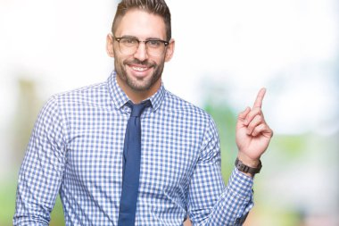 Yüzünde kocaman bir gülümseme ile izole arka plan üzerinde gözlük takan genç iş adamı kameraya bakarak yan el ve parmak ile işaret.