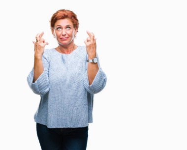 Umut ve gözleri kapalı geçiş parmaklarıyla gülümseyen izole arka plan üzerinde kış kazak giyen Atrractive üst düzey beyaz Kızıl saçlı kadın. Şans ve batıl kavramı.