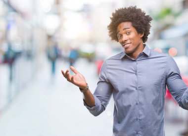 İzole arka plan clueless ve şaşkın bir ifadeyle kollar ve eller kaldırdı Afro Amerikan adam. Şüphe kavramı.