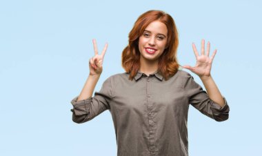 Genç güzel kadın gösterilen ve parmakları ile işaret izole arka plan yüzünden kendinden emin ve mutlu gülümseyerek süre yedi numara.