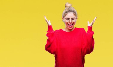 Kızgın ve silah ile başarı için deli kutluyor izole arka plan üzerinde kırmızı kazak ve gözlük giyen genç güzel sarışın kadın kaldırdı ve heyecanlı çığlık gözler kapalı. Kazanan kavramı