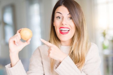 Ev çok mutlu el ve parmak ile işaret taze patates tutan genç güzel kadın