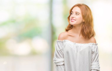 Genç güzel kadın uzak tarafına yüzünde, doğal ifade gülümseme ile seyir izole arka plan yüzünden. Kendine güvenen gülüyor.