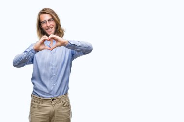 Yakışıklı delikanlı aşık kalp simgesi ve elleriyle şekil gösteren gülümseyen izole arka plan üzerinde gözlük takan uzun saçlı. Romantik kavramı.