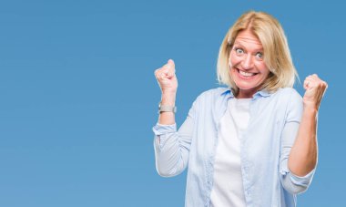 Gülümseyen ve başarı için çığlık orta yaş sarışın kadın izole arka plan çok mutlu ve heyecanlı kaldırdı, silah ile kazanan jest yapıyor. Kutlama kavramı.