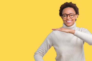 Büyük ve büyük boy işaret, ölçü birimi sembol gösteren ellerle eller izole arka plan üzerinde gözlük takan genç güzel Afrikalı-Amerikalı kadın. Kameraya bakarak gülümsüyordu. Ölçüm kavramı.