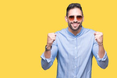 Yakışıklı delikanlı izole arka plan kutlama üzerinde güneş gözlüğü takıyor şaşırttı ve başarı için kaldırdı kollarını açarak hayret ve gözleri açık. Kazanan kavramı.
