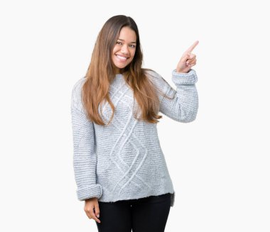 Kameraya bakarak yan el ve parmak ile işaret Kazak yüzünde kocaman bir gülümseme ile izole arka plan üzerinde giyen genç güzel esmer kadın.