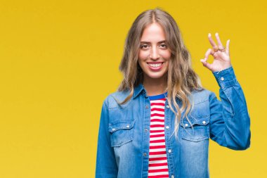 Gülümseyen izole arka plan üzerinde güzel sarışın genç kadın el ve parmaklar ok işaretiyle yapıyor olumlu. Başarılı ifade.