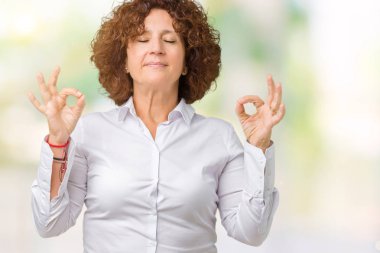 Güzel orta ager üst düzey businees kadın izole arka plan üzerinde dinlenmek ve gülümseyen gözlerle parmak ile meditasyon jest yapıyor kapalı. Yoga kavramı.