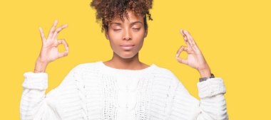 Güzel genç Afro-Amerikan kadın giyiyor kış kazak izole arka plan üzerinde dinlenmek ve gülümseyen gözlerle kapalı parmak jestle meditasyon yapıyor. Yoga kavramı.