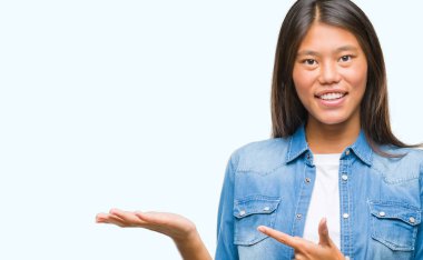 Genç Asyalı kadın üzerinden hayran ve el ile sunulması ve parmak ile işaret ederken kameraya gülümseyen izole arka plan.