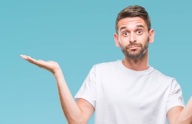 İzole arka plan clueless ve şaşkın bir ifadeyle kollar ve eller kaldırdı genç yakışıklı adam. Şüphe kavramı.