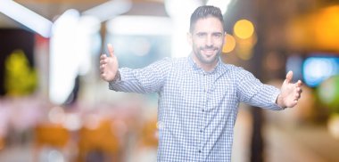 Yakışıklı delikanlı sarılmak için kollarını açarak gülümseyerek kameraya bakarak izole arka plan üzerinde. Neşeli ifade kucaklayan mutluluk.