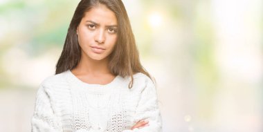 İzole arka plan şüpheci ve sinir, onaylamayan ifade yüz çapraz kolları üzerinde kış kazak giyen genç güzel Arap kadın. Negatif kişi.