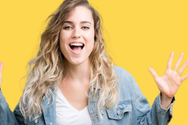 Üzerinde kot ceket giyen güzel genç sarışın kadın deli kutluyor arka plan izole ve silah ile başarı için yükseltilmiş ve açık gözleri heyecanlı çığlık hayrete düşürdü. Kazanan kavramı