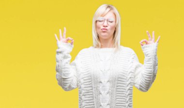 Genç güzel sarışın kadın giyiyor kış kazak ve gözlük izole arka plan üzerinde dinlenmek ve gülümseyen gözlerle kapalı parmak jestle meditasyon yapıyor. Yoga kavramı.