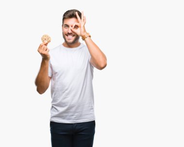 Yakışıklı delikanlı ile mutlu yüz el parmaklarının arasından seyir göz üzerinde ok işaretiyle yapıyor gülümseyen izole arka plan üzerinde çikolata çerez yemek