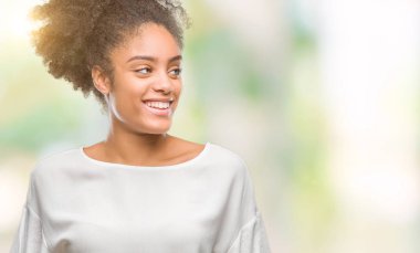Uzak tarafına yüzünde, doğal ifade gülümseme ile seyir izole arka plan üzerinde genç afro Amerikalı kadın. Kendine güvenen gülüyor.