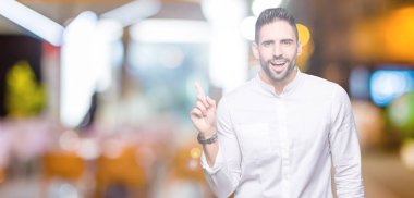 Kameraya bakarak yan el ve parmak ile işaret eden genç iş adamı yüzünde kocaman bir gülümseme ile izole arka plan üzerinde.