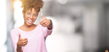 Güzel genç Afro-Amerikan kadın gözlük izole arka plan onaylama üzerinde el ile pozitif jest yapıyor gülümseyen ve başarı için mutlu başparmak. Kamera, kazanan jest arıyorsunuz.