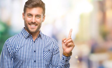 Kameraya bakarak yan el ve parmak ile işaret eden genç yakışıklı adam yüzünde kocaman bir gülümseme ile izole arka plan üzerinde.