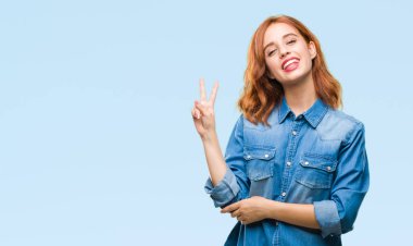 Genç güzel kadın mutlu yüz zafer işareti yaparken kameraya göz kırpıyor ile gülümseyen izole arka plan yüzünden. İki numaralı.