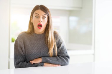 Evde korkuyor ve şok sürpriz ifade, korku ve heyecan yüz ile kış kazak giyen genç güzel kadın.