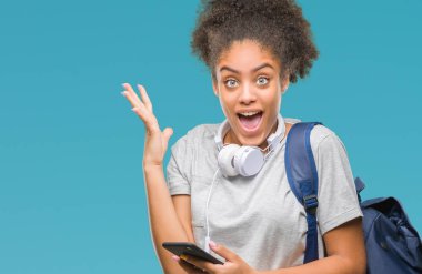 Sırt çantası tutan genç güzel afro Amerikan öğrenci kadın büyük gülümseme ile çığlık zaferini kutluyor ve ellerini kaldırdı arka plan çok mutlu ve heyecanlı, kazanan ifade izole