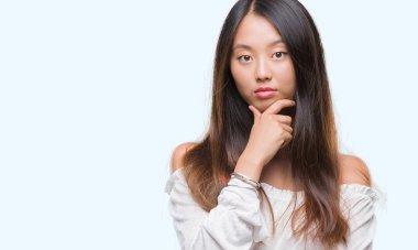 Genç Asyalı kadın emin çapraz kollar ve çeneme kaldırdı el ile gülümseme ile kameraya bakarak izole arka plan üzerinde. Pozitif düşünce.