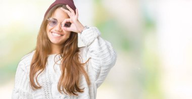 Genç güzel esmer hipster kadın gülümsüyor, parmakları ile mutlu yüz üzerinden seyir göz el ile ok jest yapıyor izole arka plan üzerinde güneş gözlüğü takıyor.