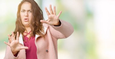 Artı boyutu genç kadın güzel üzerinde kış palto giyiyor arka plan korkuyor ve dehşete şokta bağırarak el ile korku ifade dur hareketi ile izole. Panik kavramı.